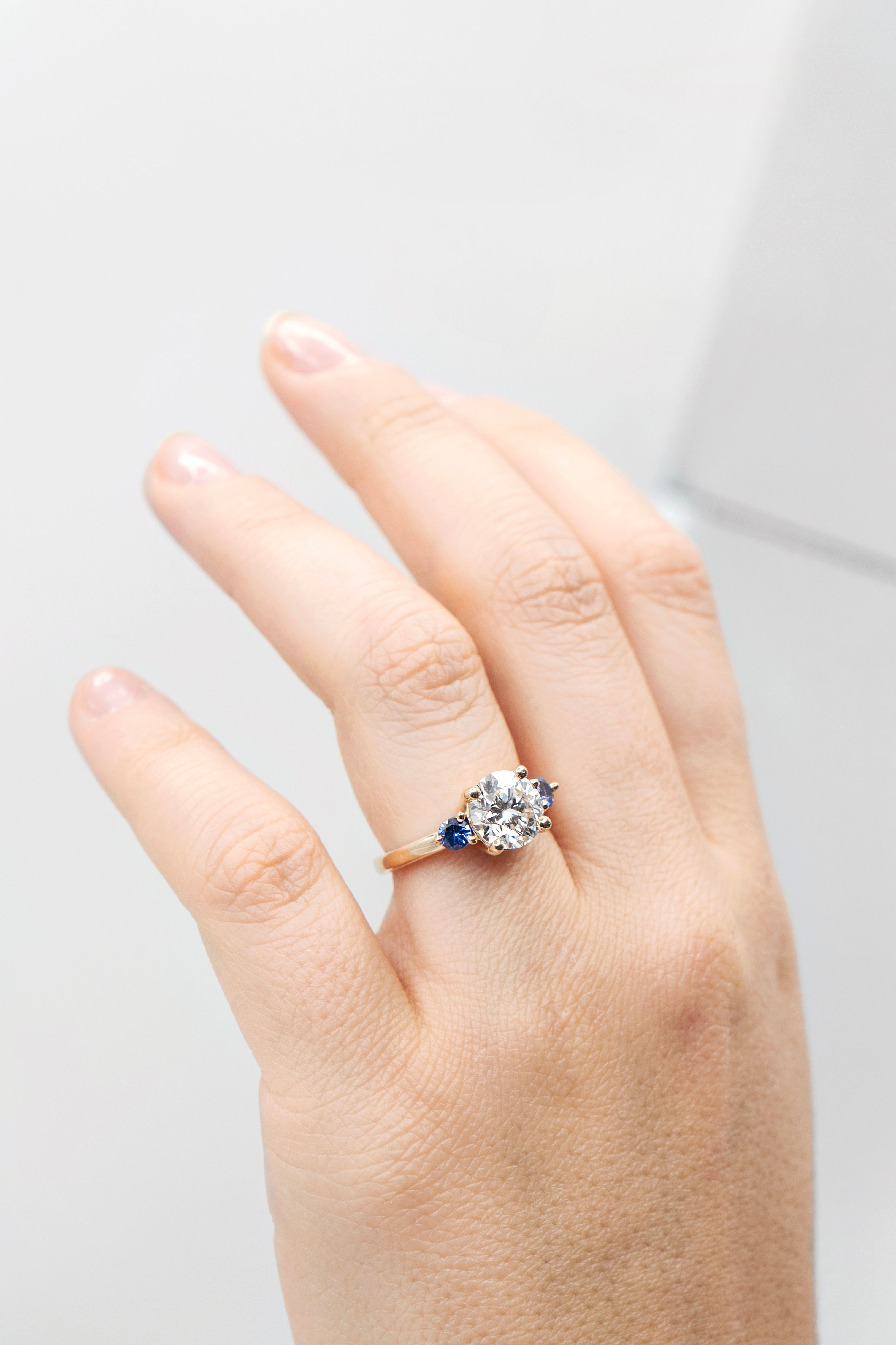 Round lab-grown diamond engagement ring with two sapphires
