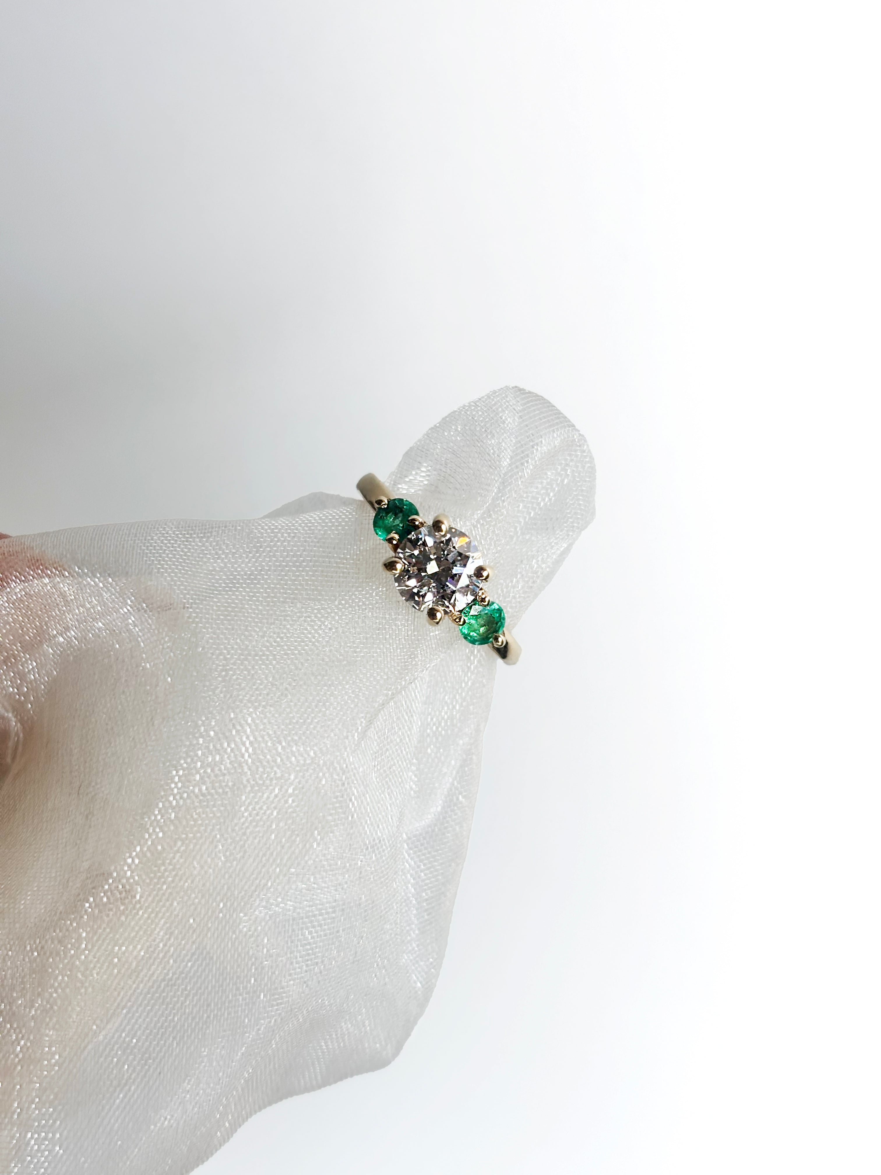 Round diamond ring with emerald side stones