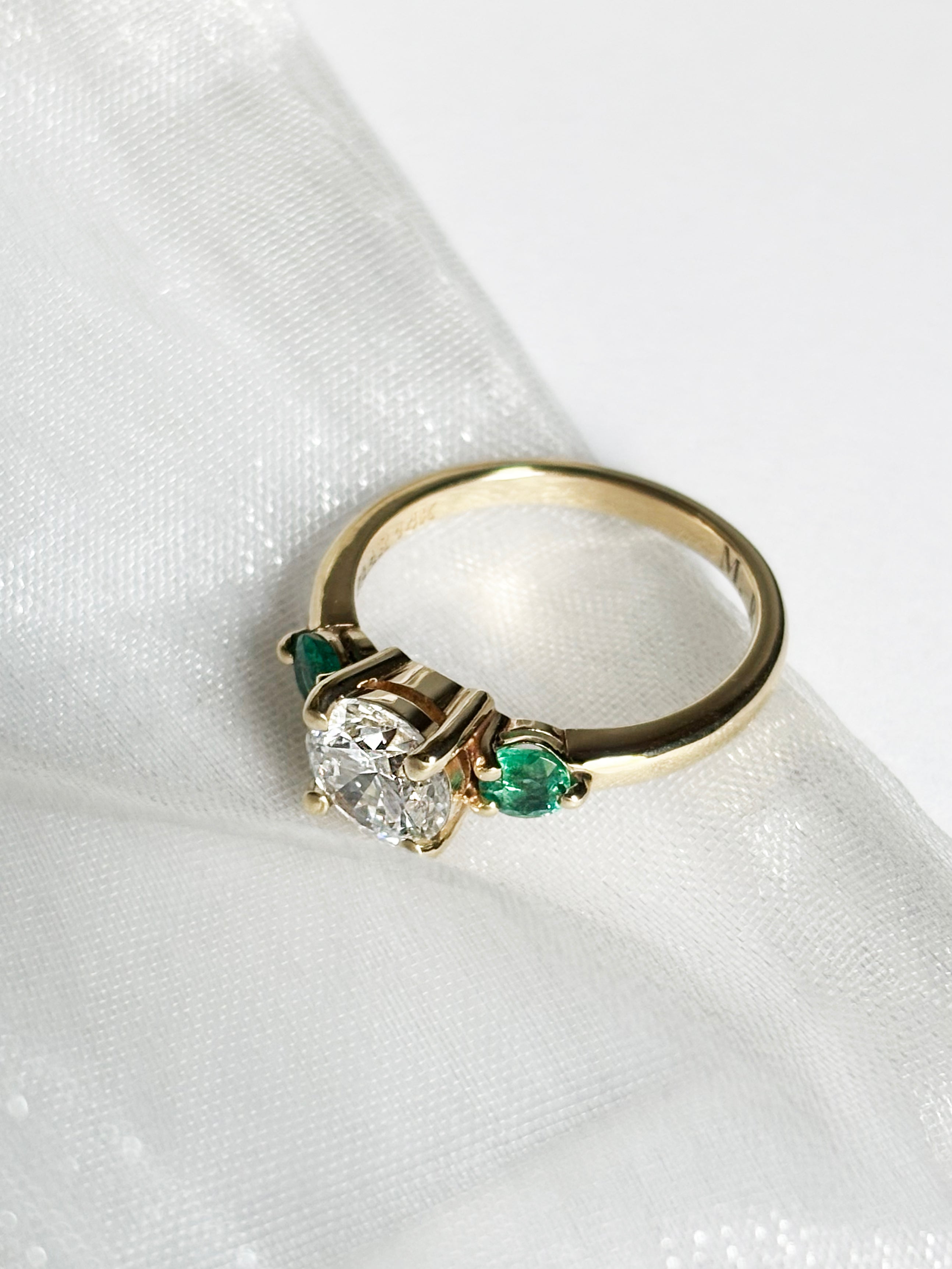 Round diamond ring with emerald side stones
