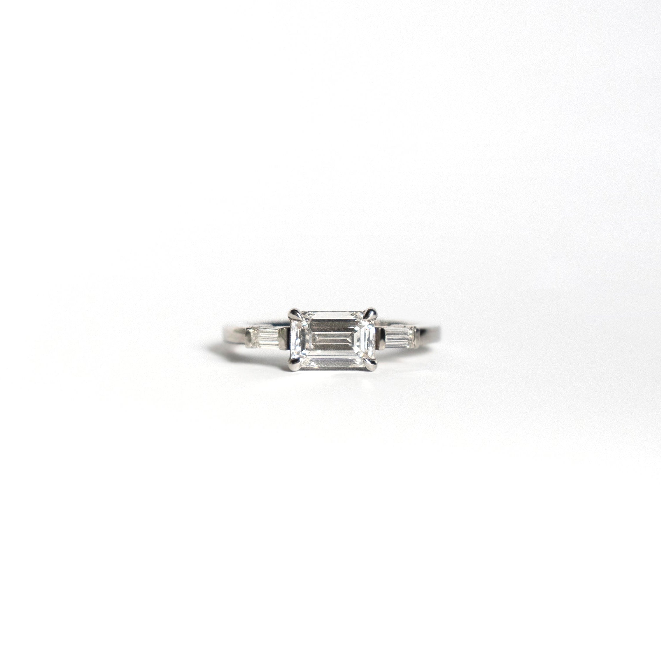 Emerald-cut diamond engagement ring set east-west with two baguette diamonds