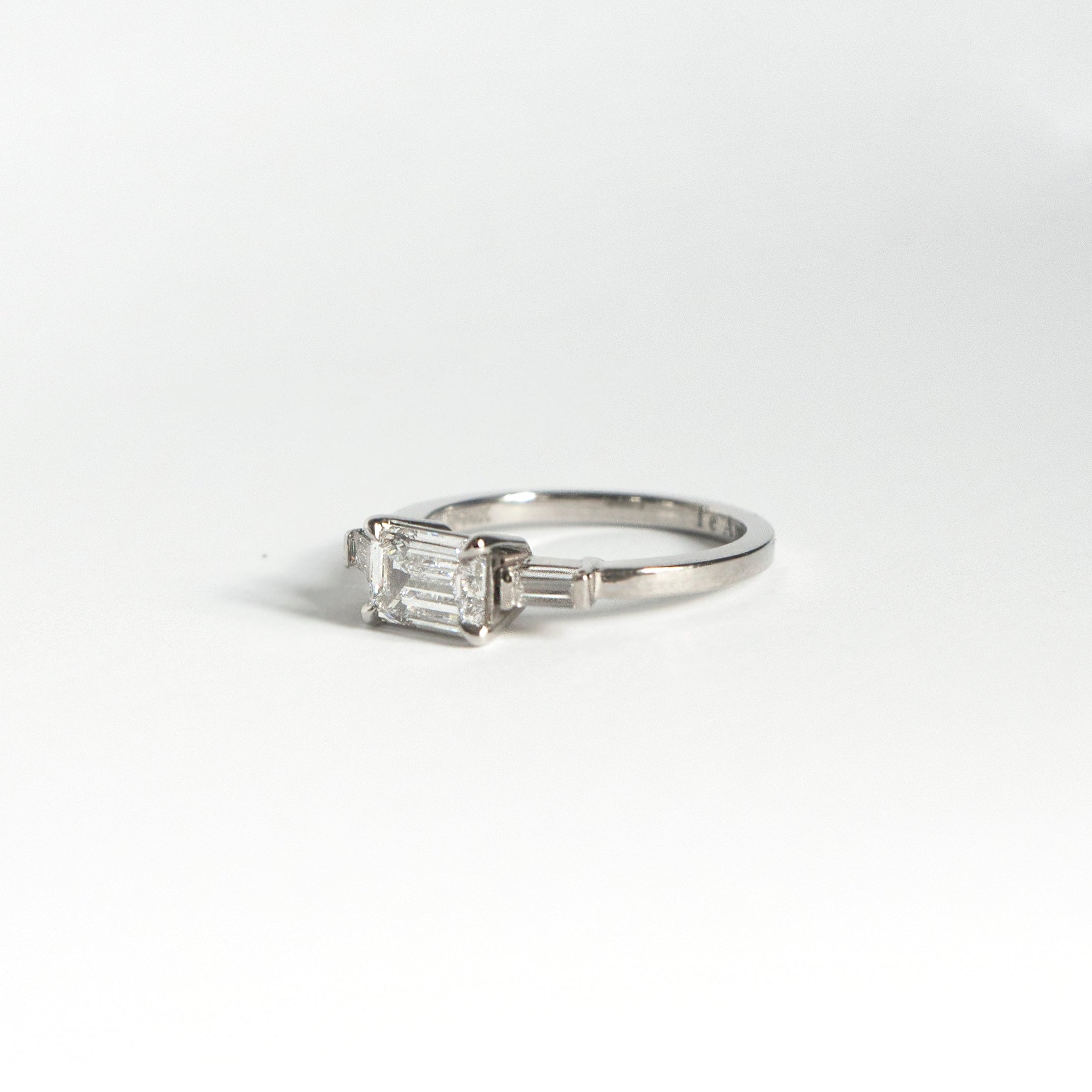 Emerald-cut diamond engagement ring set east-west with two baguette diamonds