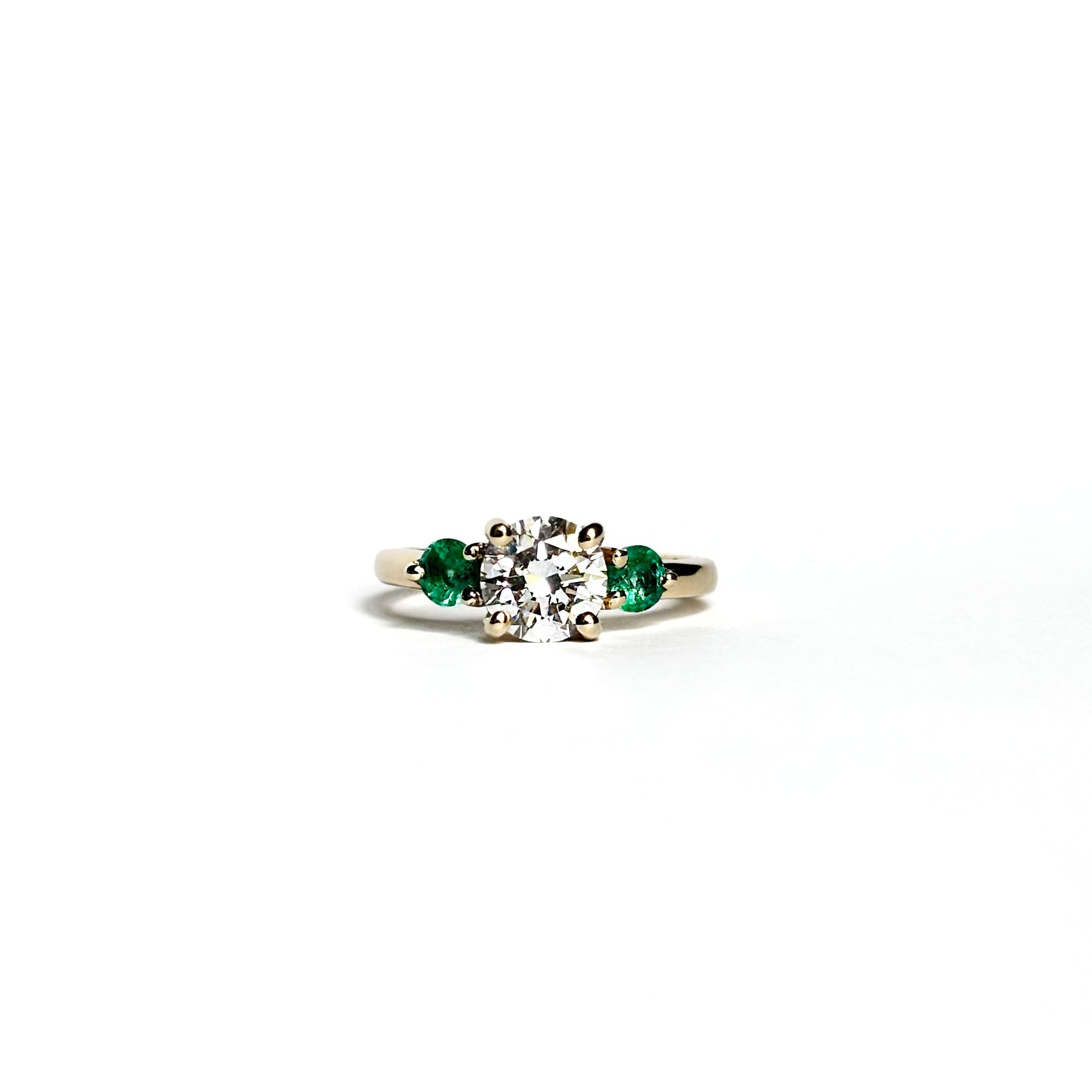 Round diamond ring with emerald side stones