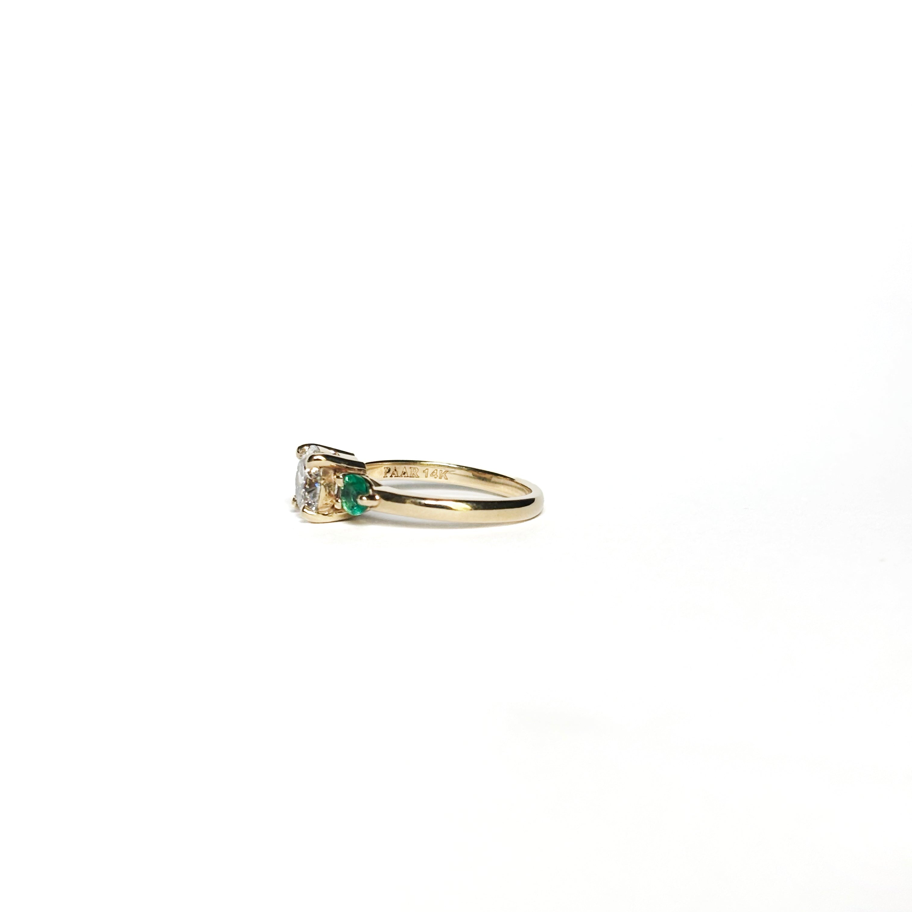 Round diamond ring with emerald side stones