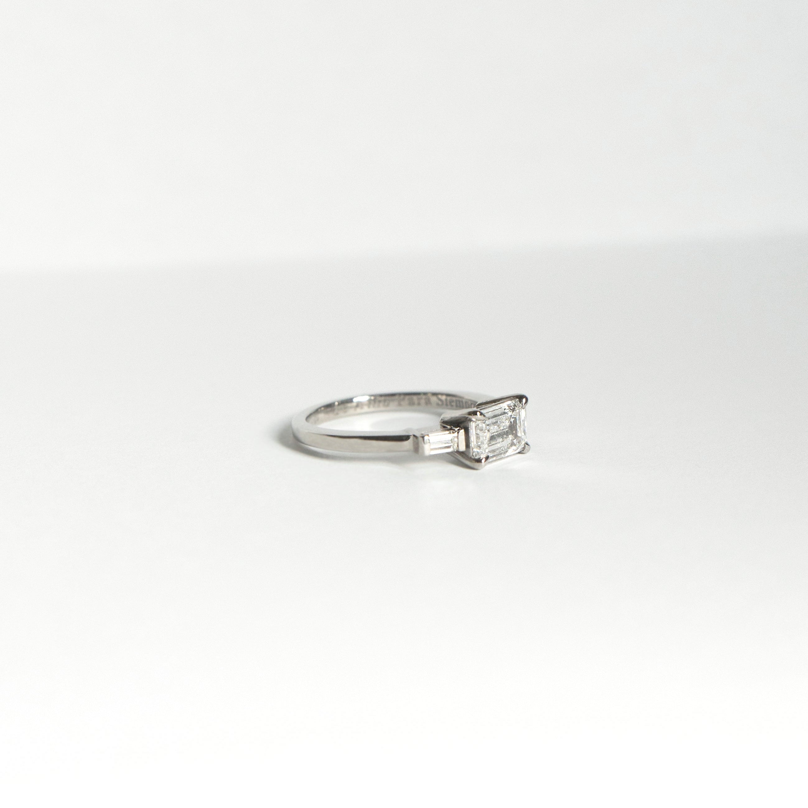 Emerald-cut diamond engagement ring set east-west with two baguette diamonds